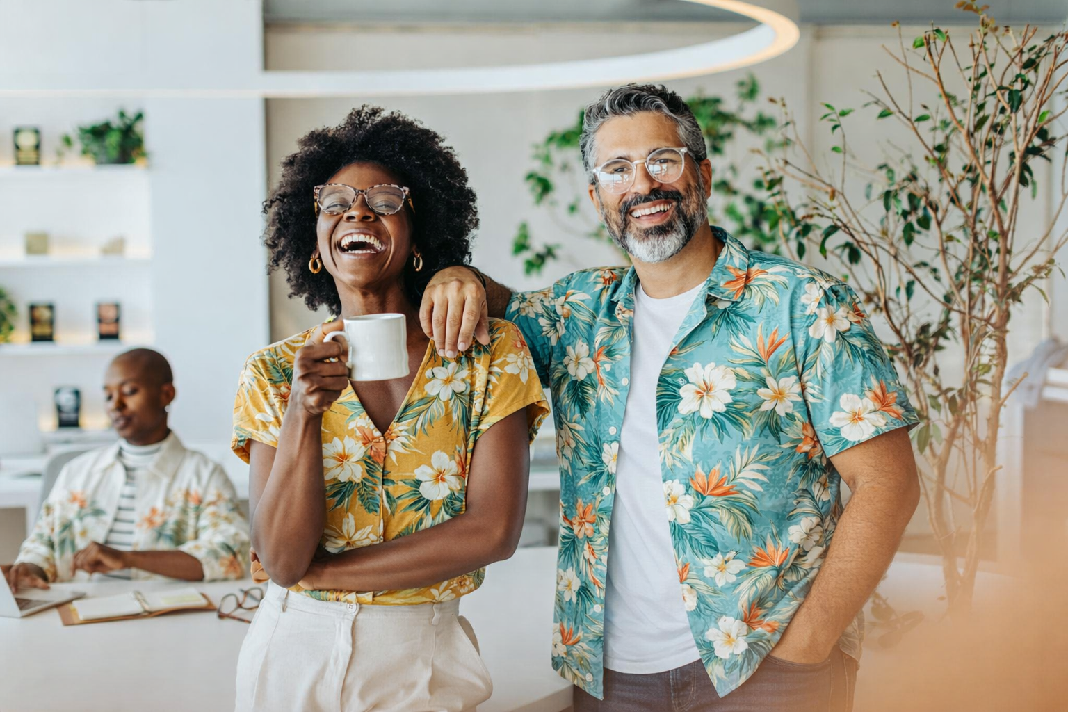 Happy office team wearing colorful Hawaiian shirts with matching tropical patterns, smiling and enjoying a relaxed workplace moment together